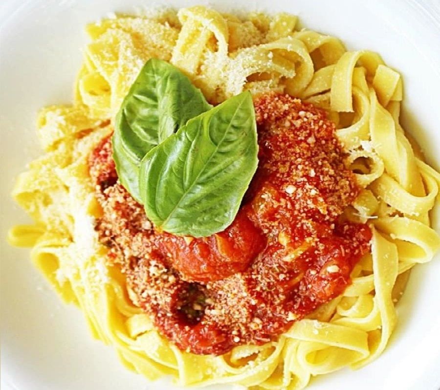 Plato de pasta con salsa de tomate y albahaca fresca.